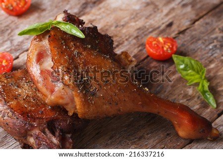 two roasted duck leg with tomatoes close up on an old table horizontal. rustic style