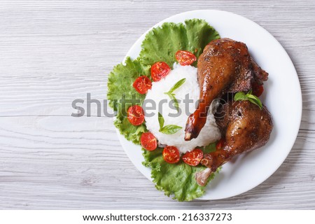 roasted duck leg with rice and vegetables on the plate. a top view of a horizontal