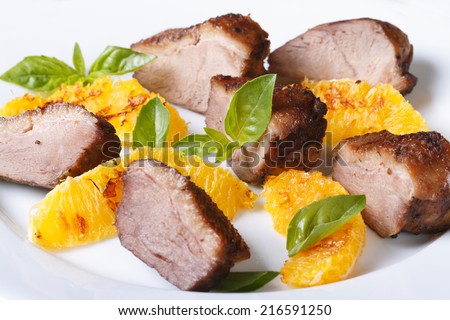 slices of roasted duck meat fillet with orange and basil close-up on a white plate. horizontal