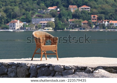 old wicker rattan chair on the seafront the Bay of Kotor. Montenegro