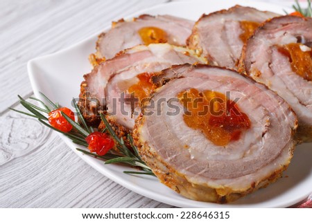 Meat roll with dried apricots and cherries closeup on a white plate. horizontal