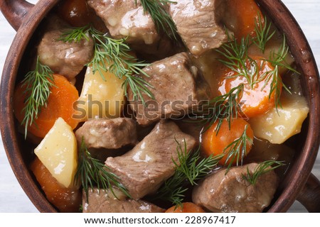 beef stew with vegetables and herbs in a pot macro. background horizontal view from the top.
