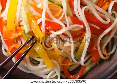 Rice noodles with peppers, carrots, onions and zucchini macro on a plate. horizontal view from above
