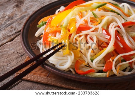Rice noodles with peppers, carrots and zucchini close-up on a plate. a horizontal