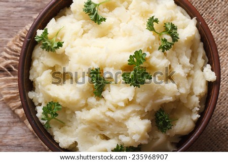 mashed potatoes with parsley in a bowl macro on the table. horizontal view from above. rustic style
