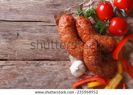 Grilled sausages with vegetables close up on an old table. horizontal view from above