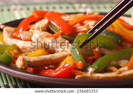 chicken with peppers, carrots macro and chopsticks on the wooden table. horizontal