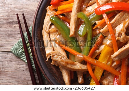 chicken with vegetables macro and chopsticks on the wooden table. horizontal view from above