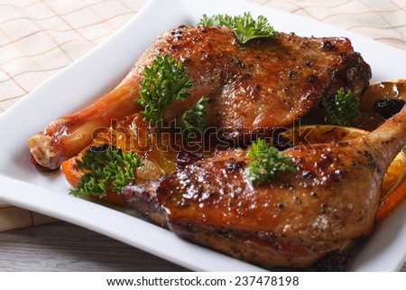 roasted duck leg with oranges on a white plate close up. horizontal