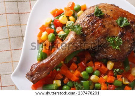 Roasted duck leg with vegetables on a plate close-up. top view of a horizontal