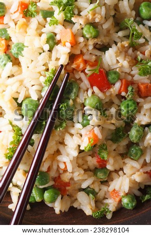 fried rice with egg, peas, carrots macro on a plate and chopsticks. vertical top view