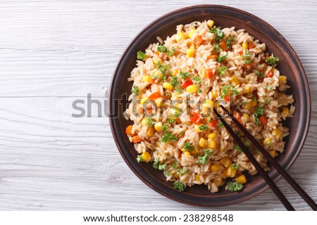 Asian fried rice with eggs, corn and parsley close-up on a plate, horizontal view from above