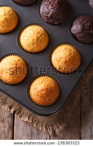 chocolate and vanilla muffins in baking dish close up on the table. Vertical view from above