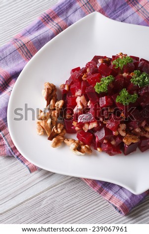 Beet salad with walnuts close-up on a white plate. vertical top view