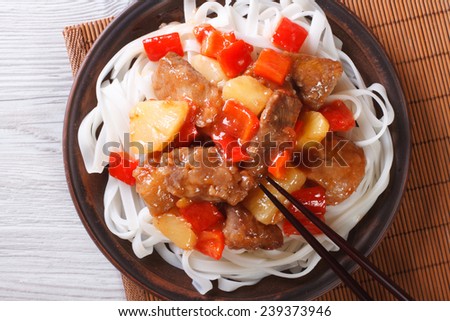 rice noodles with pork meat in sweet and sour sauce on a plate close-up. horizontal view from above