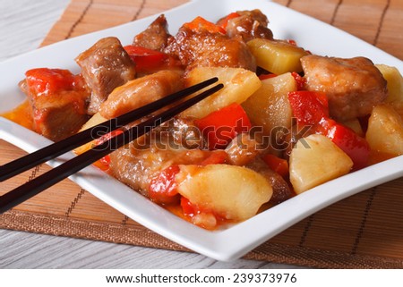 pork meat with pineapple and vegetables in sweet and sour sauce on a plate close-up. horizontal