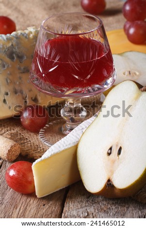Red wine in a crystal glass with cheese and fruit close-up on the table. vertical