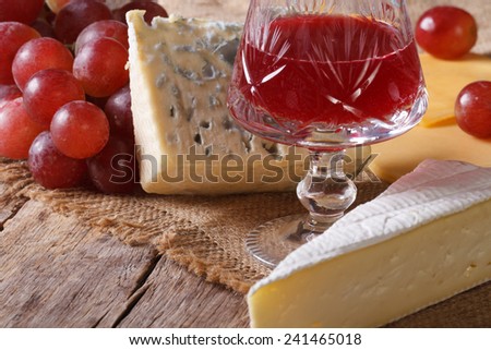 Red wine with cheese and grapes close-up on the table. horizontal