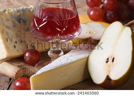 Red wine with cheese and fruit close-up on the table. horizontal