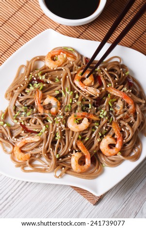 Buckwheat soba noodles with shrimp and sesame seeds close-up. vertical top view