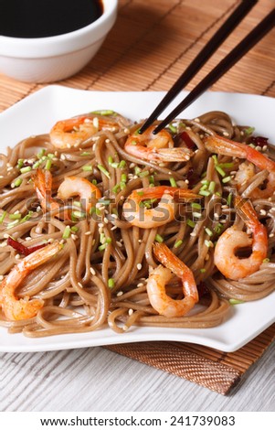 Japanese buckwheat soba noodles with shrimp and sesame seeds on a plate close-up. vertical