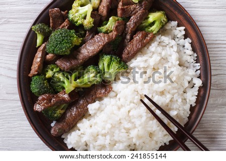 beef with broccoli and rice on a plate on the table close-up. horizontal view from above