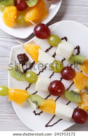 Fresh fruit on skewers with chocolate sauce closeup. vertical top view