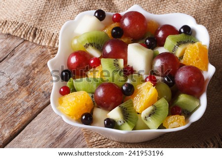Fruit salad of oranges, grapes. pears, kiwis in a white bowl closeup. horizontal
