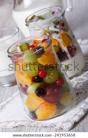 Healthy food: fresh fruit in a glass jar and yoghurt close-up on the table vertical