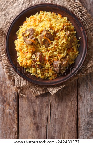 Rice with meat and vegetables on an old table close-up. vertical view above, rustic style