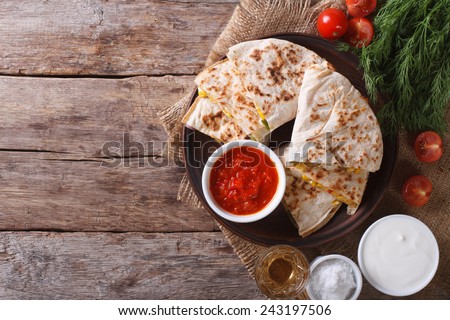 Quesadilla sliced with vegetables and sauces on the table. horizontal view from above