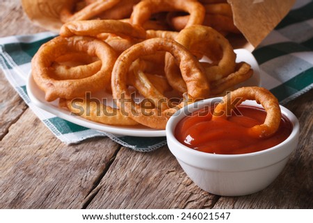 Deep fried onion rings and ketchup closeup. horizontal on the old table