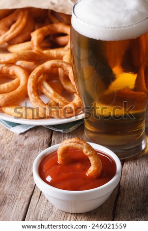 fried onion rings and a glass of beer close-up on the table. vertical