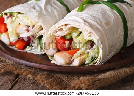 Lavash roll with chicken and vegetables close up on a plate. horizontal