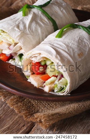 Roll burrito with chicken and vegetables close up on a plate. vertical