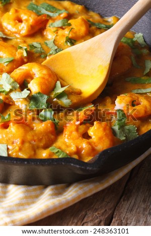 Prawns in curry sauce in a black frying pan macro. vertical, rustic style