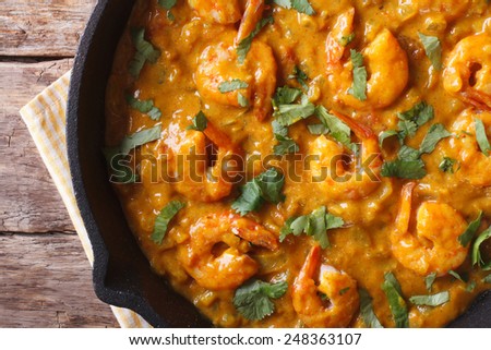 Prawns in curry sauce in a black frying pan close-up. horizontal view from above