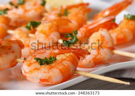 Delicious grilled shrimp on wooden skewers on a plate macro. horizontal