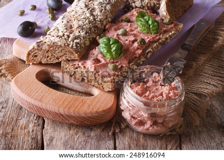 Sandwich with goose pate, capers and basil close-up on chopping board. horizontal