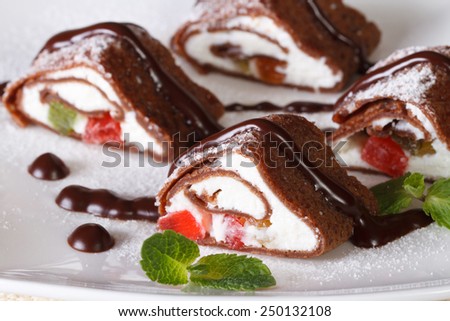 chocolate crepe rolls with cheese, fruit and mint on a white plate close-up. horizontal