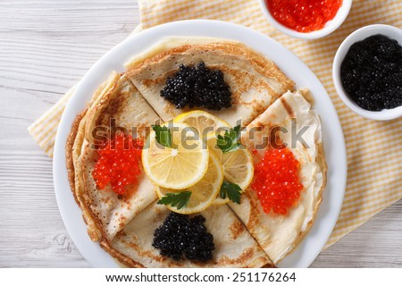 Pancakes with red and black caviar closeup, horizontal view from above