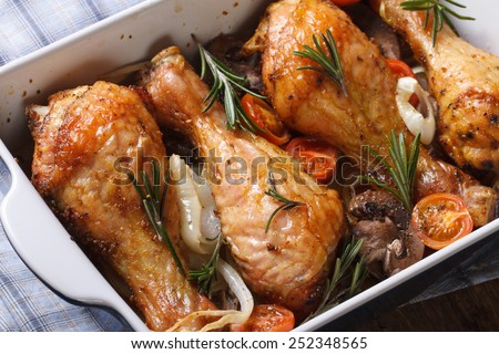 chicken legs with mushrooms in a baking dish close up on the table. horizontal view from above