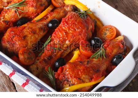 Chicken legs in tomato sauce with vegetables in a baking dish closeup. horizontal view from above