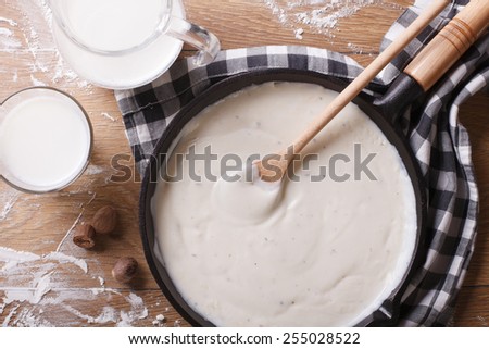 bechamel sauce in a pan and milk on the table. horizontal top view close-up