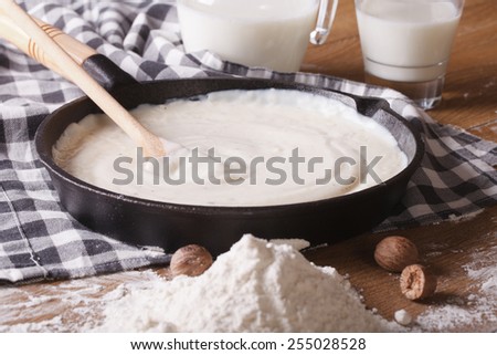 preparation of bechamel sauce in a pan and flour, milk on the table. horizontal