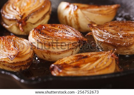 Caramelized onion halves with balsamic vinegar in a pan close-up, horizontal