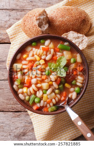 Italian minestrone soup and bread on the table. Vertical view from above