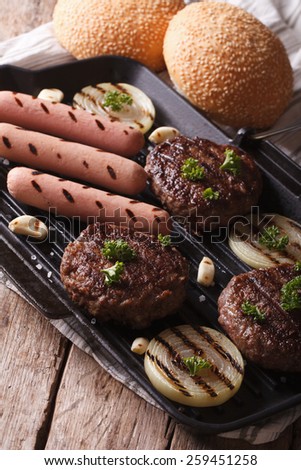 burgers and sausages with vegetables on a grill pan closeup. Vertical
