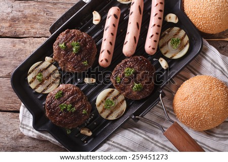 Burger and sausages on a grill pan. horizontal view from above close up