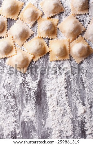 Italian uncooked ravioli with flour on the table . vertical view from above